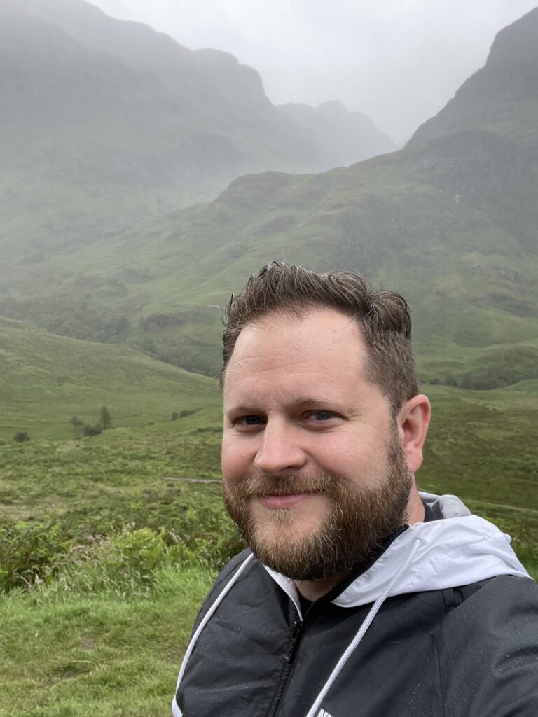 Jared standing in the foreground of the Three Sisters at Glencoe, Scottish Highlands.